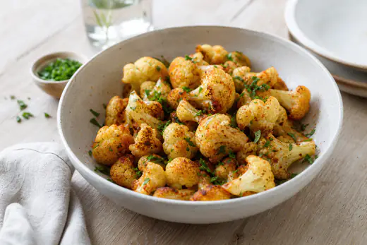 Bouquets de chou-fleur rôtis, dorés et caramélisés, saupoudrés de paprika et de persil, dans un bol creux