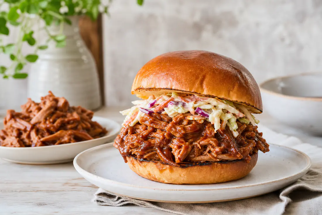 Porc effiloché brillant de sauce barbecue, garni dans un petit pain brioché avec de la salade de chou