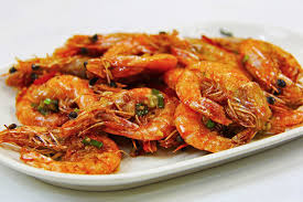 Crevettes dorées et épicées cuites dans l'airfryer, servies avec une sauce.