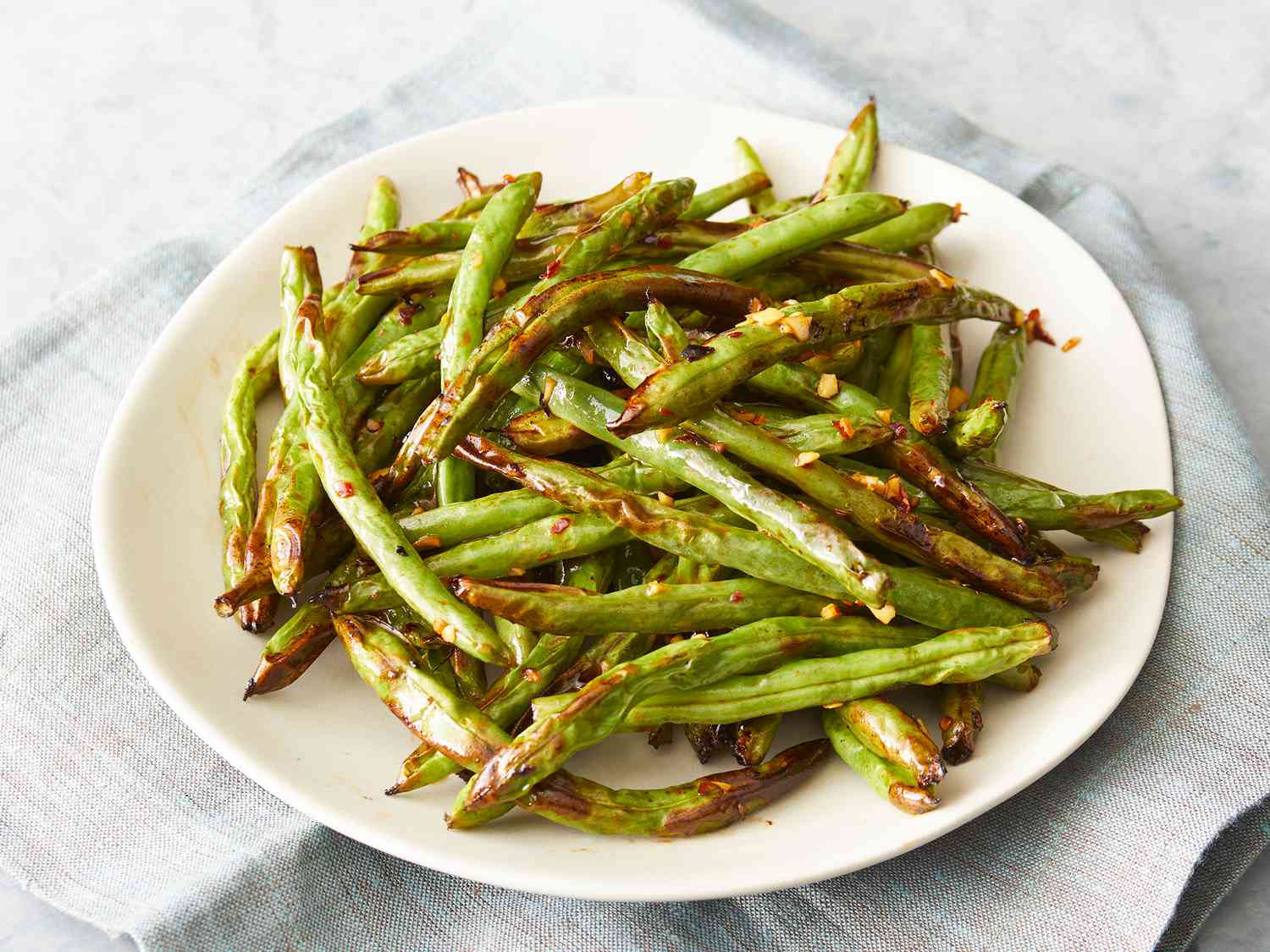 Haricots verts grillés et dorés, cuits dans l'airfryer, servis dans un bol.
