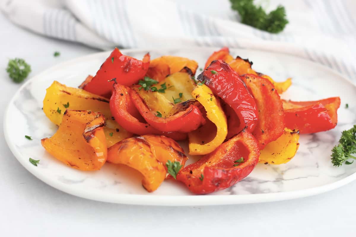 Poivrons colorés grillés, cuits dans l'airfryer, servis dans une assiette.