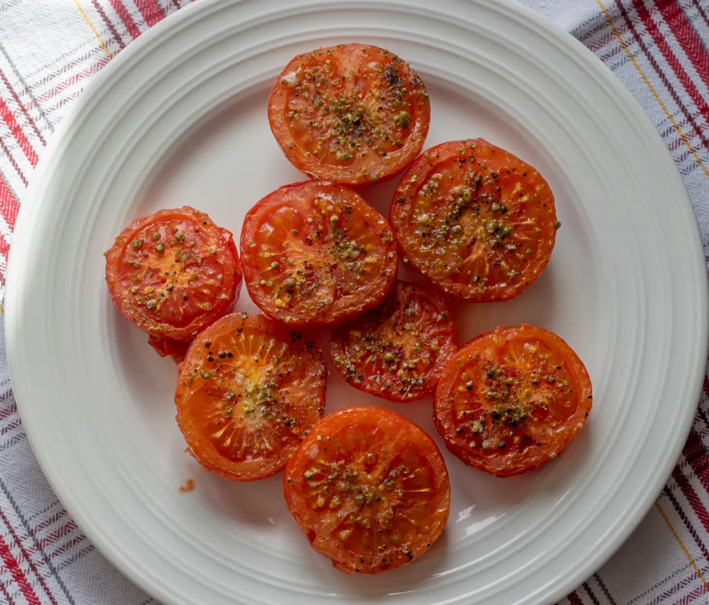 Tomates grillées, caramélisées, cuites dans l'airfryer, garnies de basilic frais.