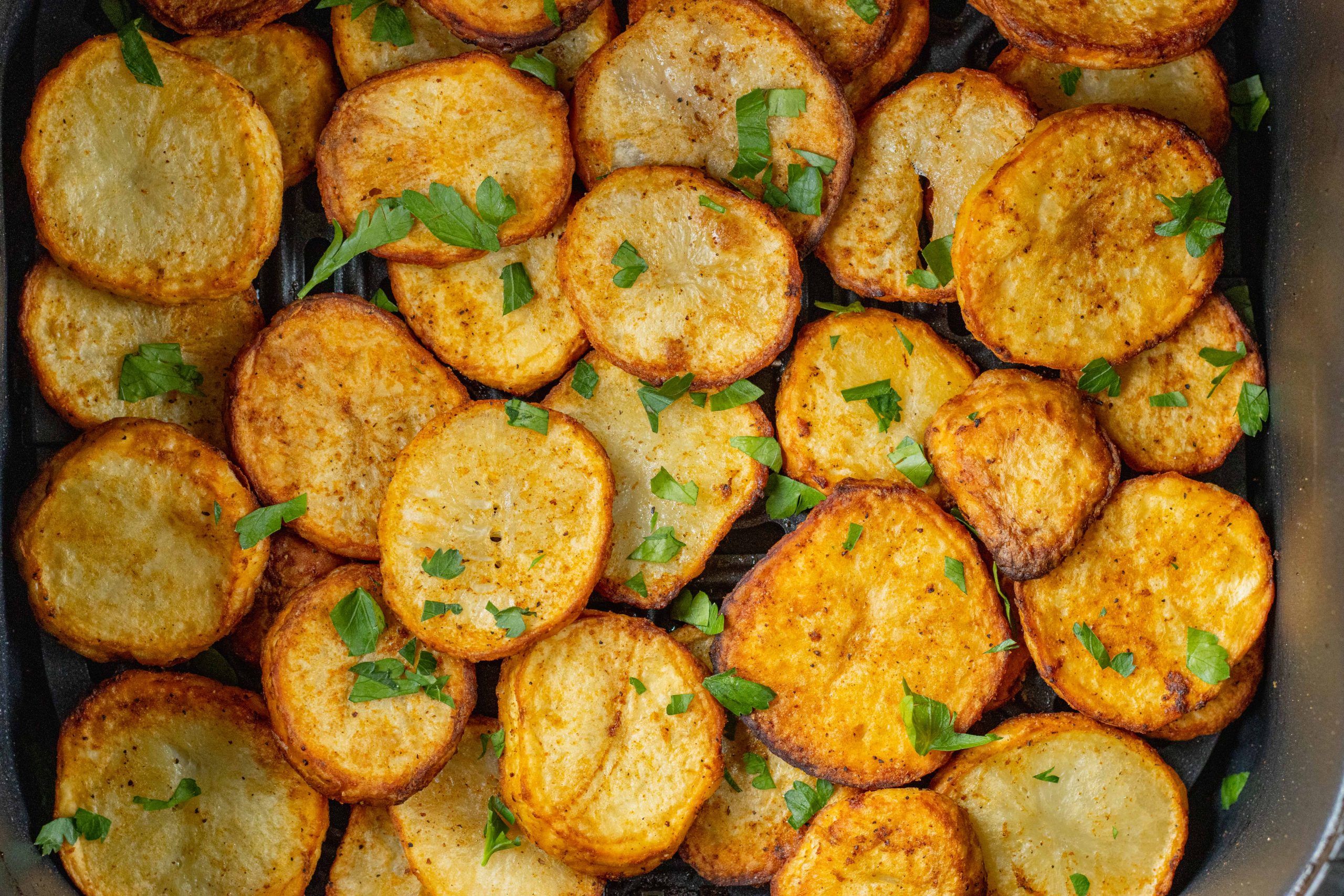Tranches de pommes de terre dorées et croustillantes dans un panier d'airfryer.