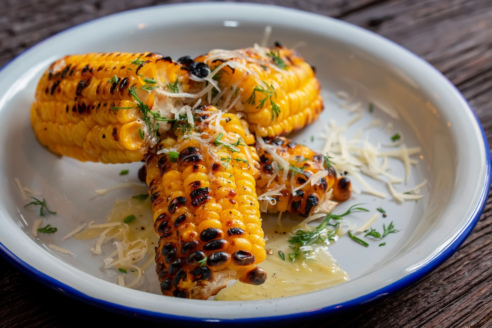 Maïs en épi grillé et doré, cuit dans l'airfryer, servi avec du beurre fondu.