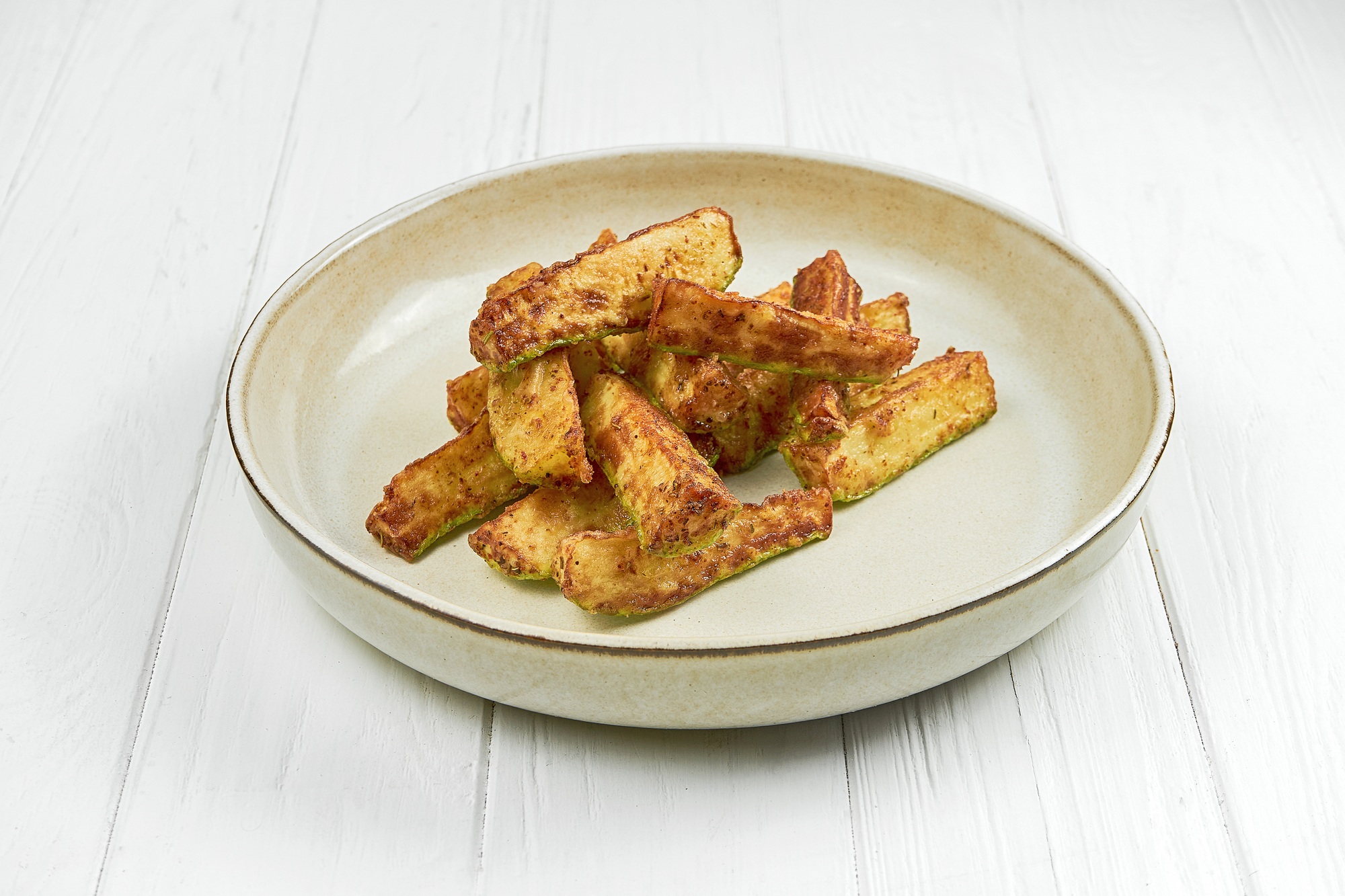 Rondelles de zucchini dorées et cuites dans l'airfryer, servies sur une assiette.