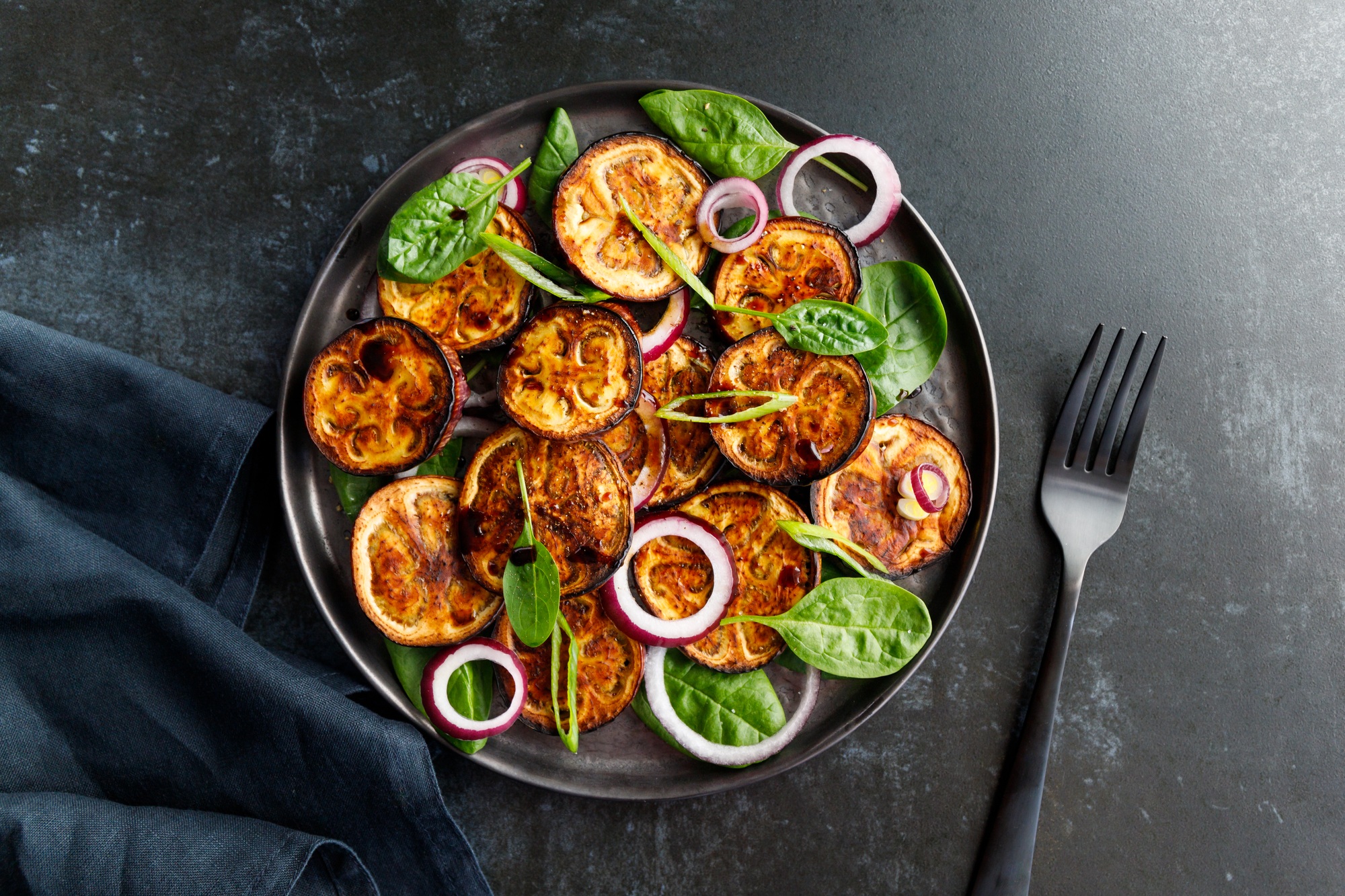 Aubergine grillée et dorée, cuite dans l'airfryer, servie dans une assiette.