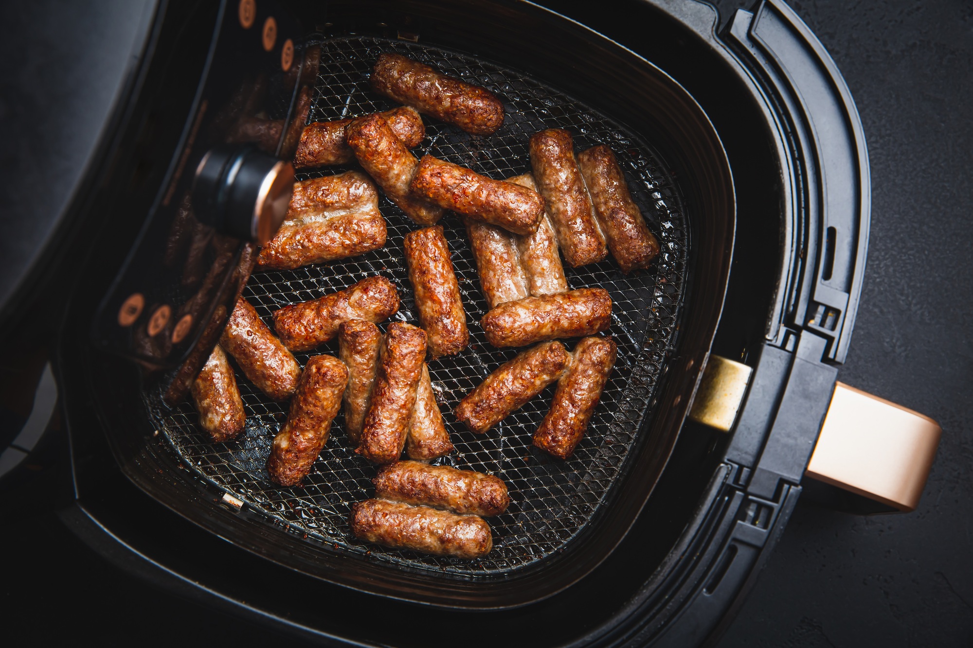 Saucisses fraîches cuites dans l'airfryer, dorées et juteuses.
